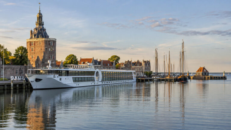 Small river cruise ship at Enkhuizen Netherlands harbor on IJsselmeer, Dutch historic waterfront and masts, no people