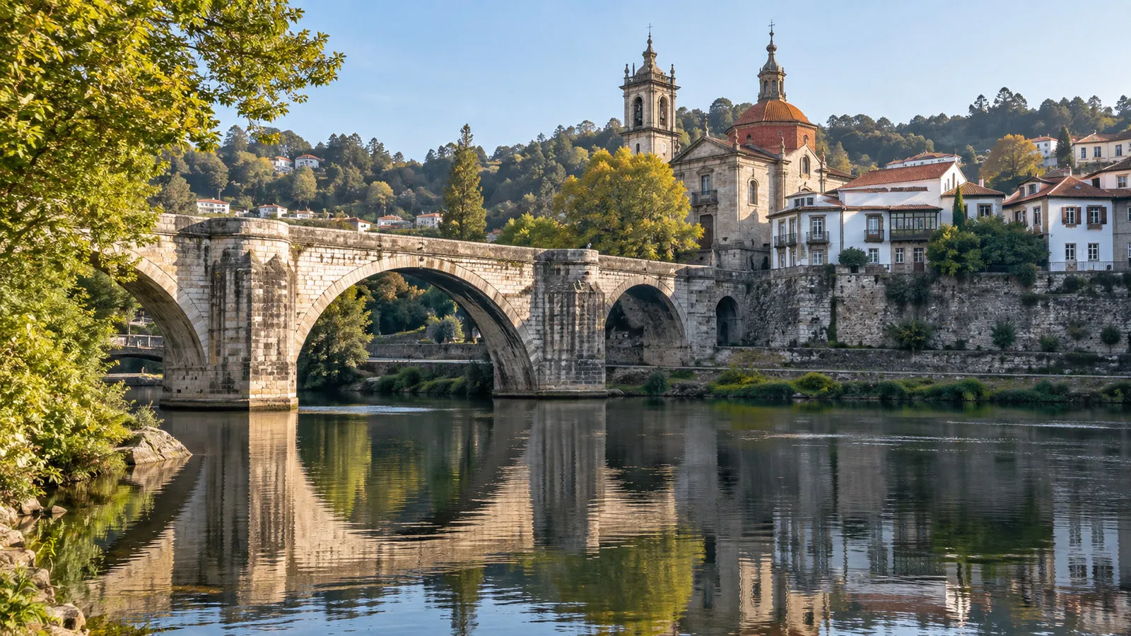 Historic Sao Goncalo Bridge crossing Tamega River in Amarante Portugal with church and old town behind, no people