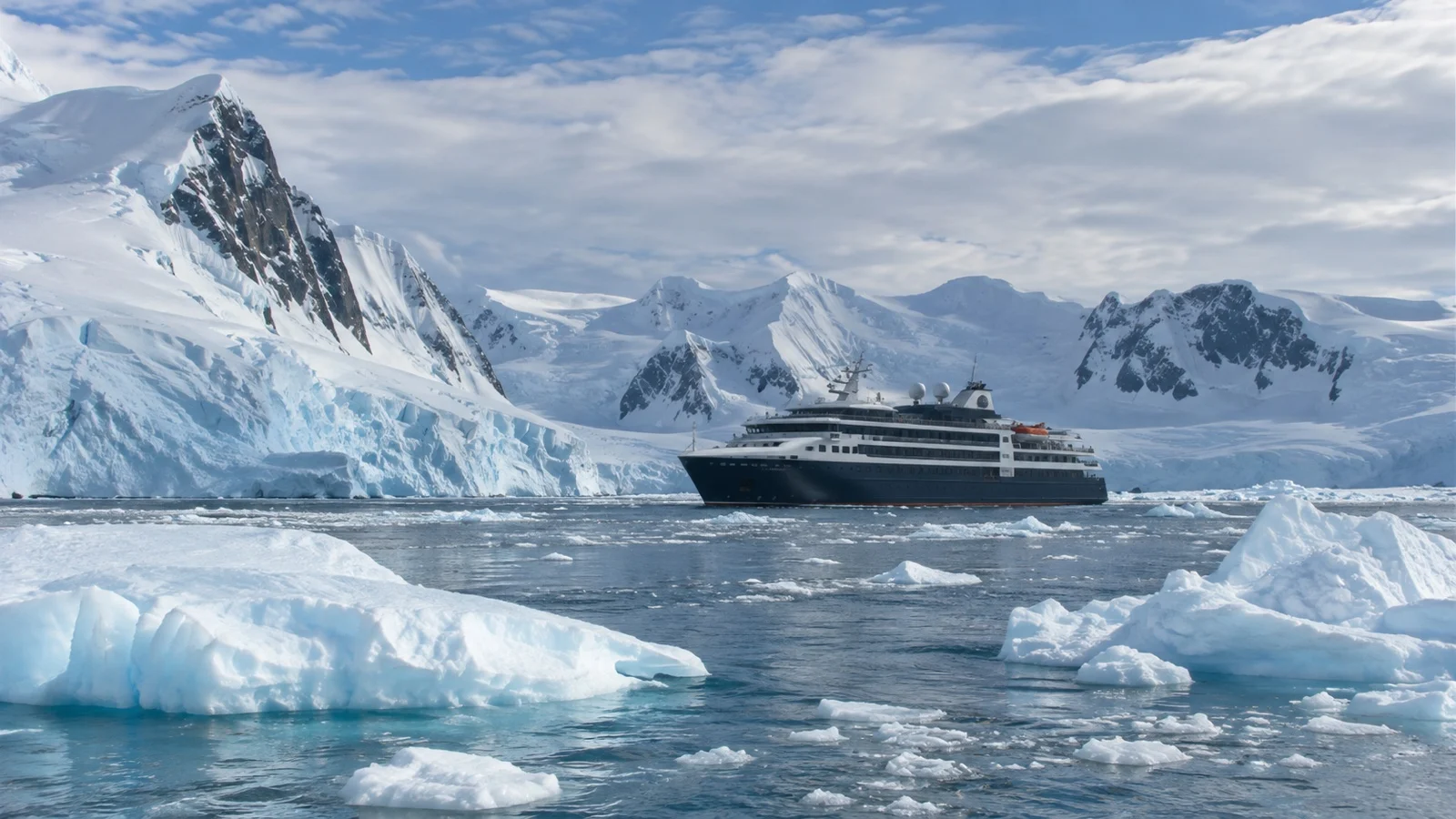 Compact expedition cruise ship among Antarctic icebergs