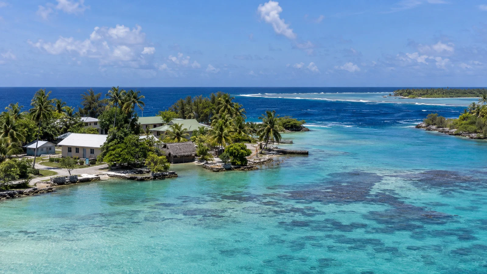 Tetamanu village and southern pass of Fakarava atoll with small tropical buildings and clear lagoon water