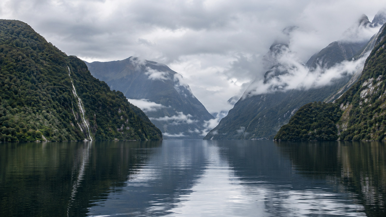 Doubtful Sound Patea Fiordland New Zealand broad still water between steep forested mountains under low cloud, no people