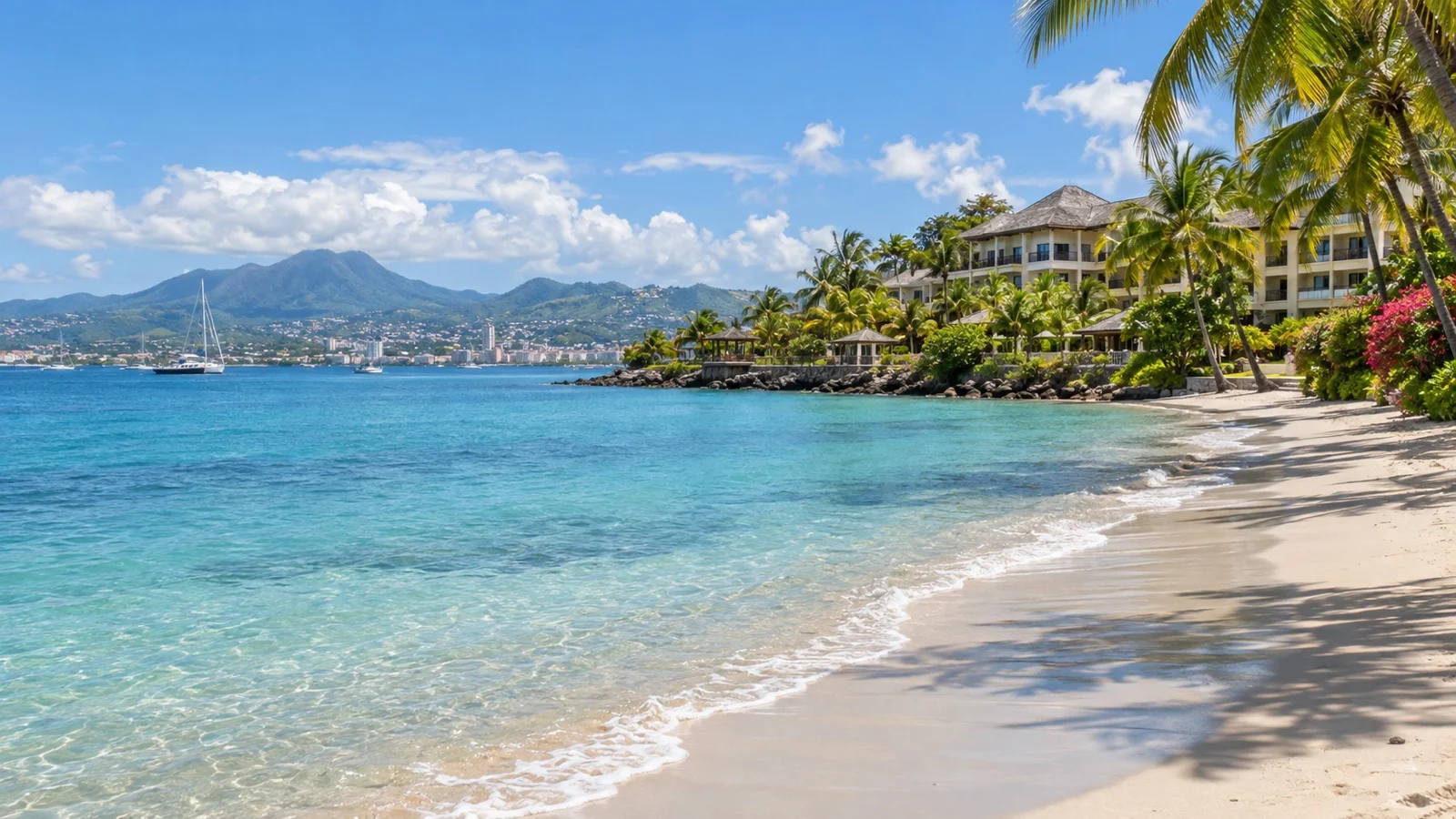 Trois-Îlets beach across the bay from Fort-de-France with upscale resort buildings, palms and turquoise sea
