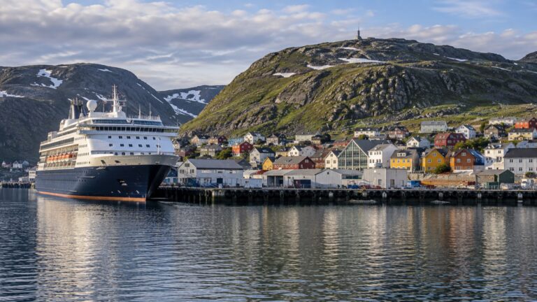 A cruise ship docked by colorful buildings in Honningsvåg harbor