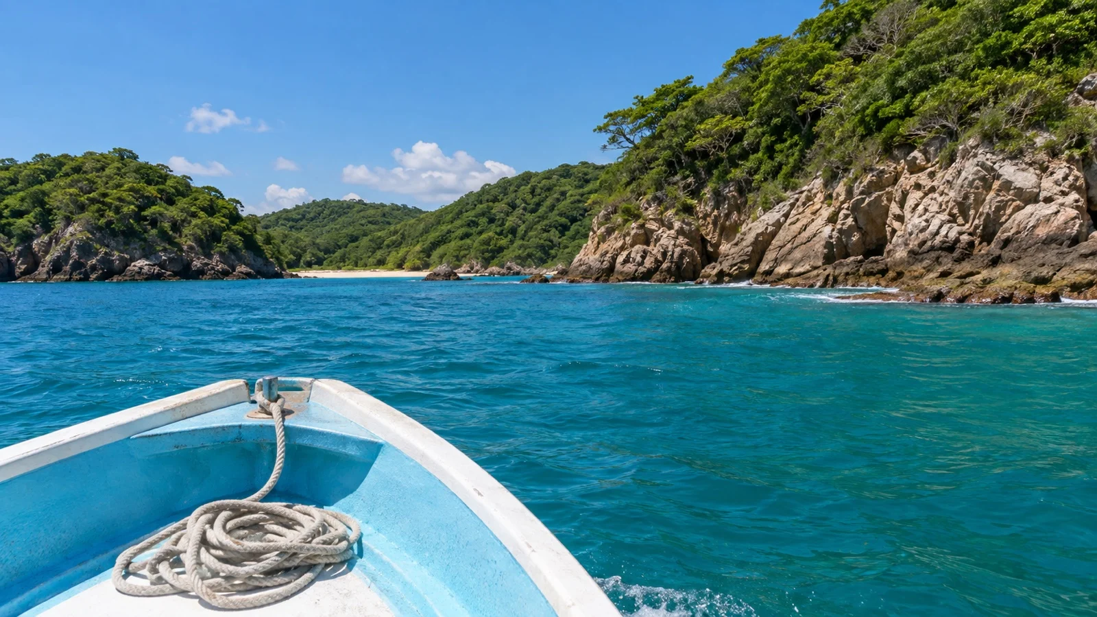 Small boat crossing one of Huatulco’s bays between green headlands