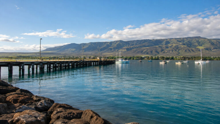 Kaunakakai harbor Molokai Hawaii with long pier, calm ocean, small boats and low island shoreline, no people