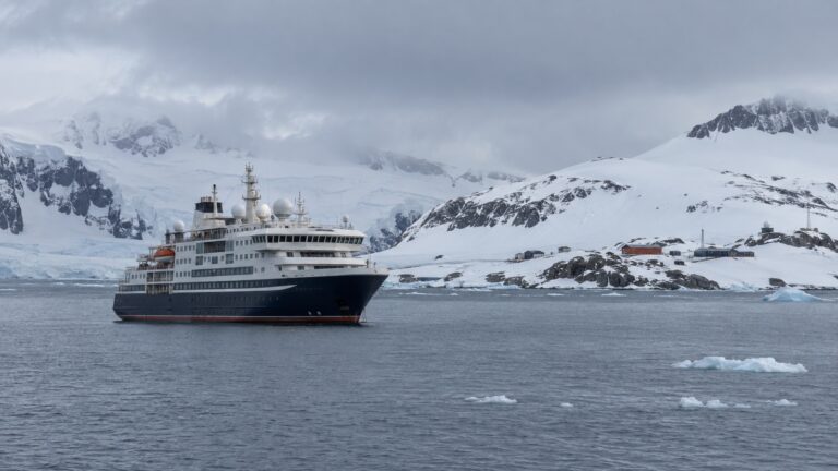 Antarctic expedition cruise ship offshore from King George Island among cold gray water and low snowy hills
