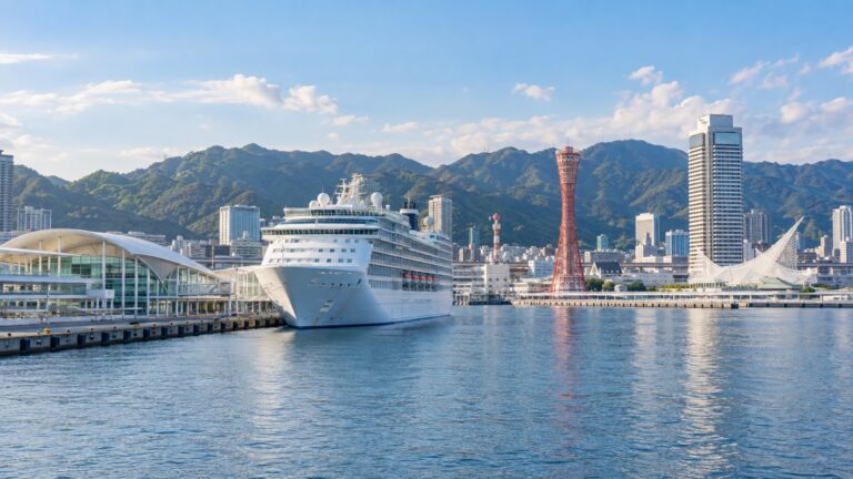 Kobe Port Terminal cruise berth with a white cruise ship beside Kobe Harbor and Mount Rokko behind the city