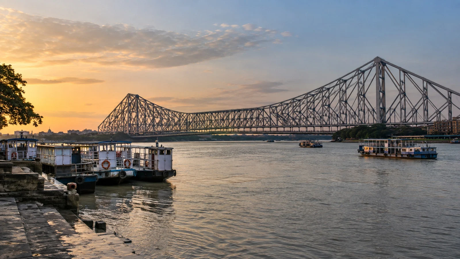 Howrah Bridge spanning Hooghly River at Kolkata India with riverboats and ghats, no people visible