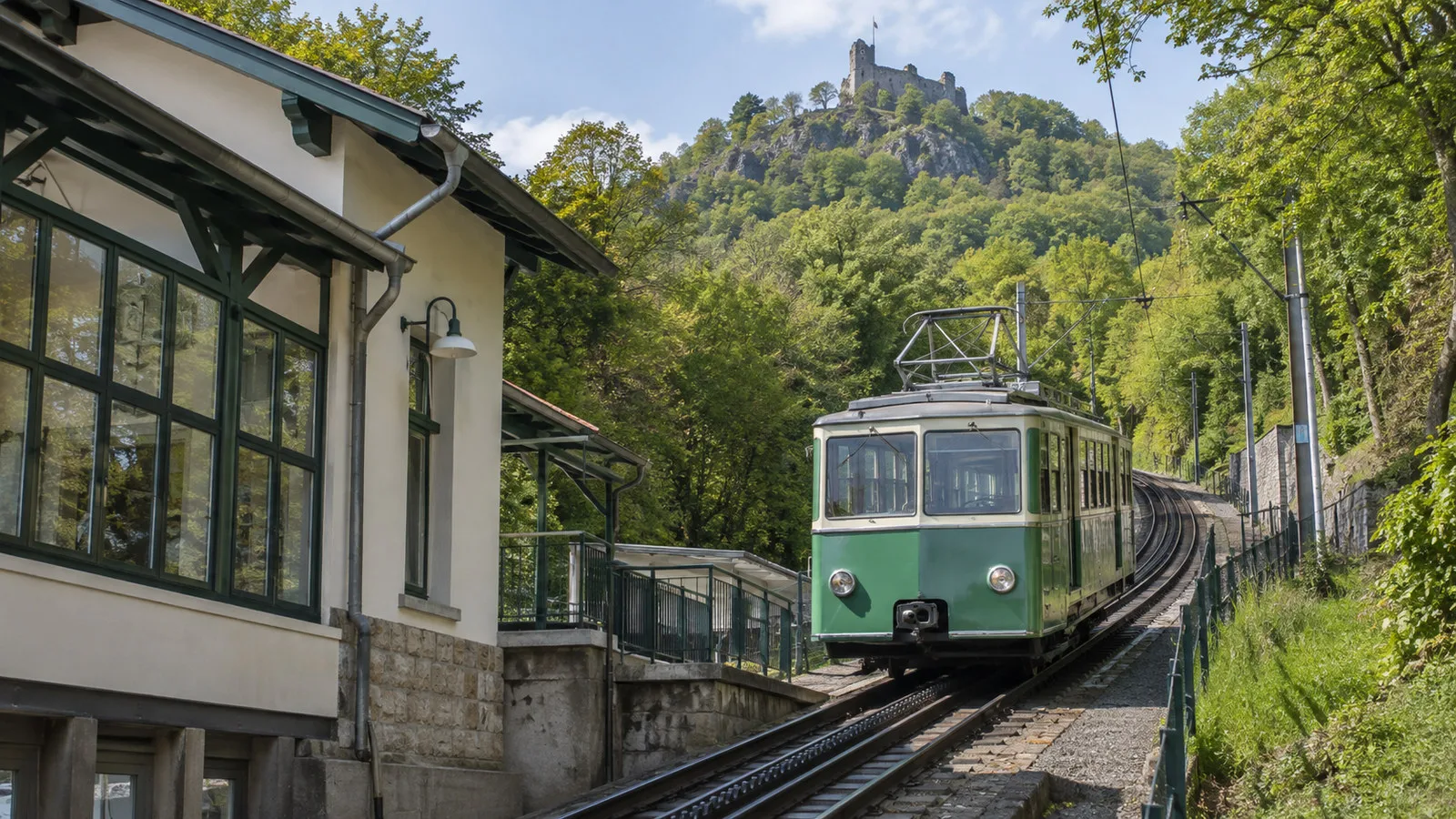 Drachenfelsbahn rack railway train at lower station in Konigswinter Germany heading up forested hill, no people