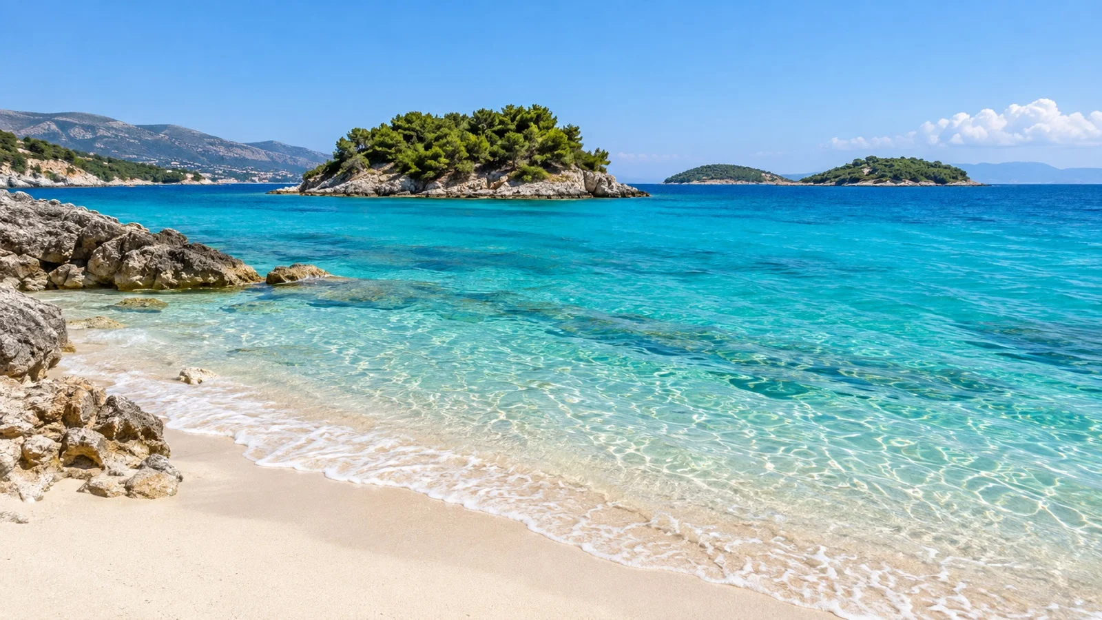 Clear turquoise water and small green islands off a quiet Ksamil beach