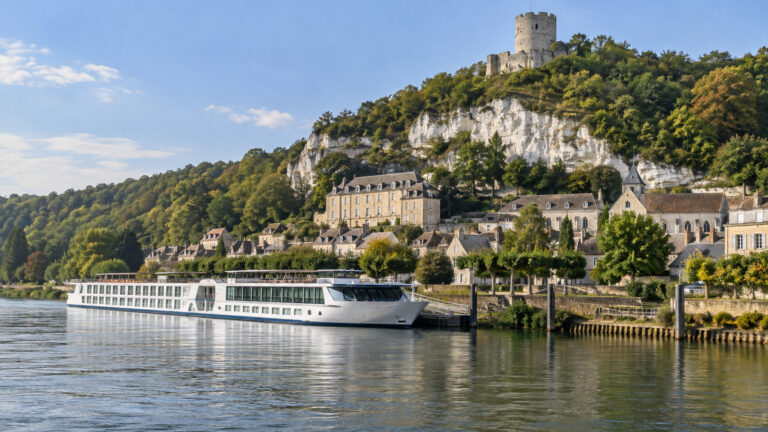 Seine river cruise vessel moored by La Roche-Guyon village and chalk cliff