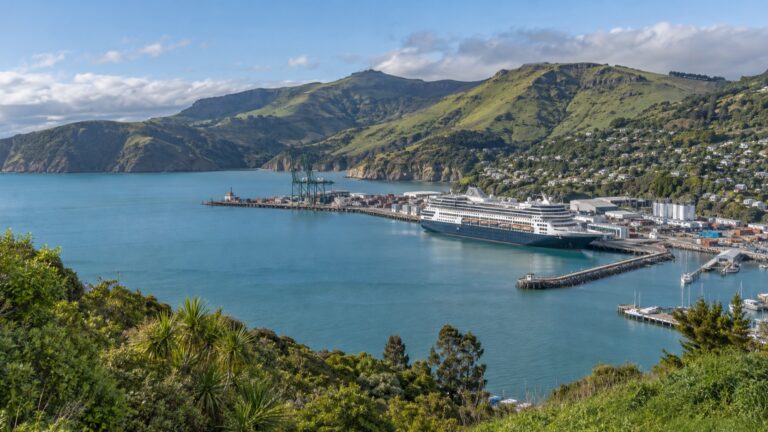 Cruise ship in Lyttelton harbor beneath green volcanic hills
