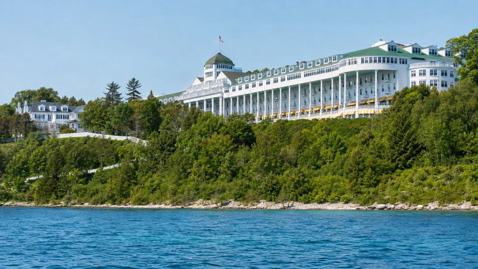 Mackinac Island shoreline with Grand Hotel white long veranda above blue lake, no people