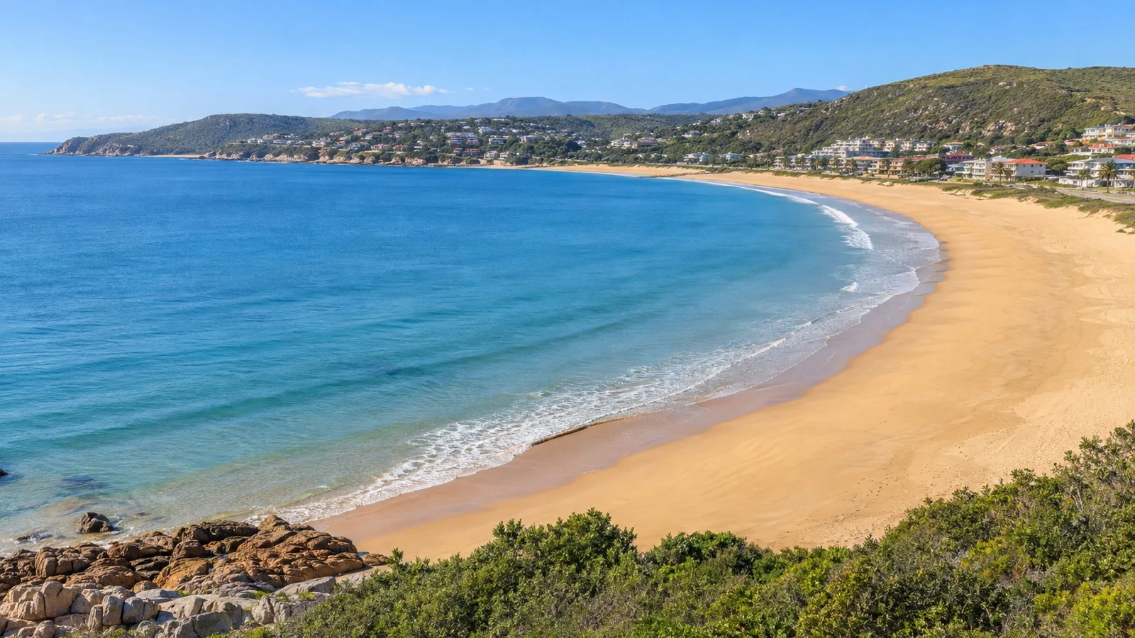 Curved sandy shoreline and blue water at Santos Beach, Mossel Bay