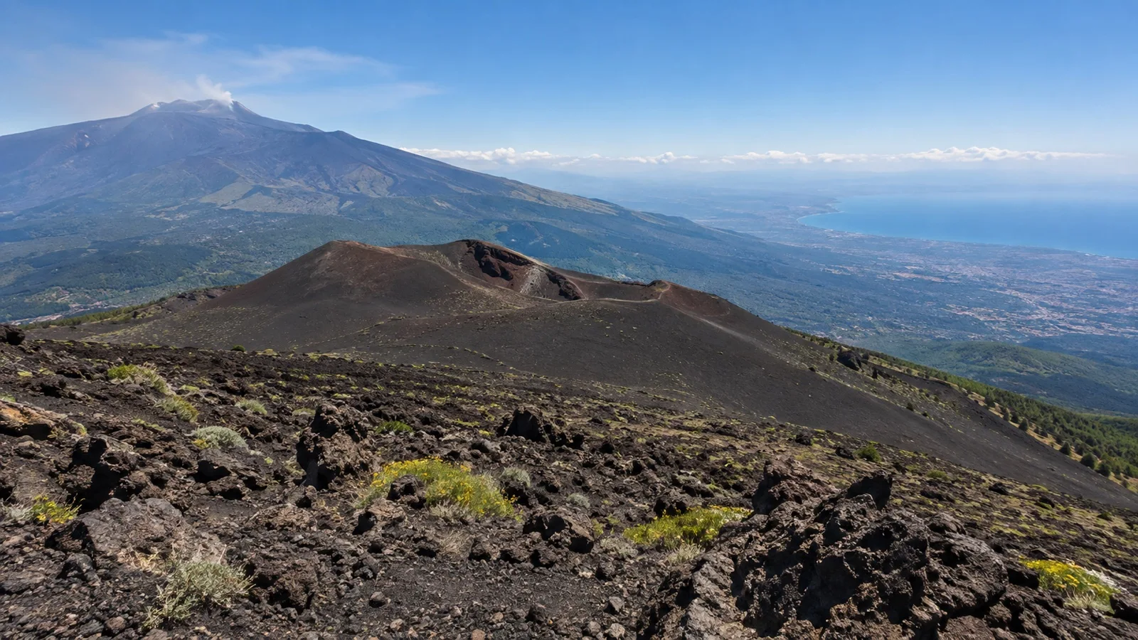 Dark lava field and crater slopes on Mount Etna above Sicily