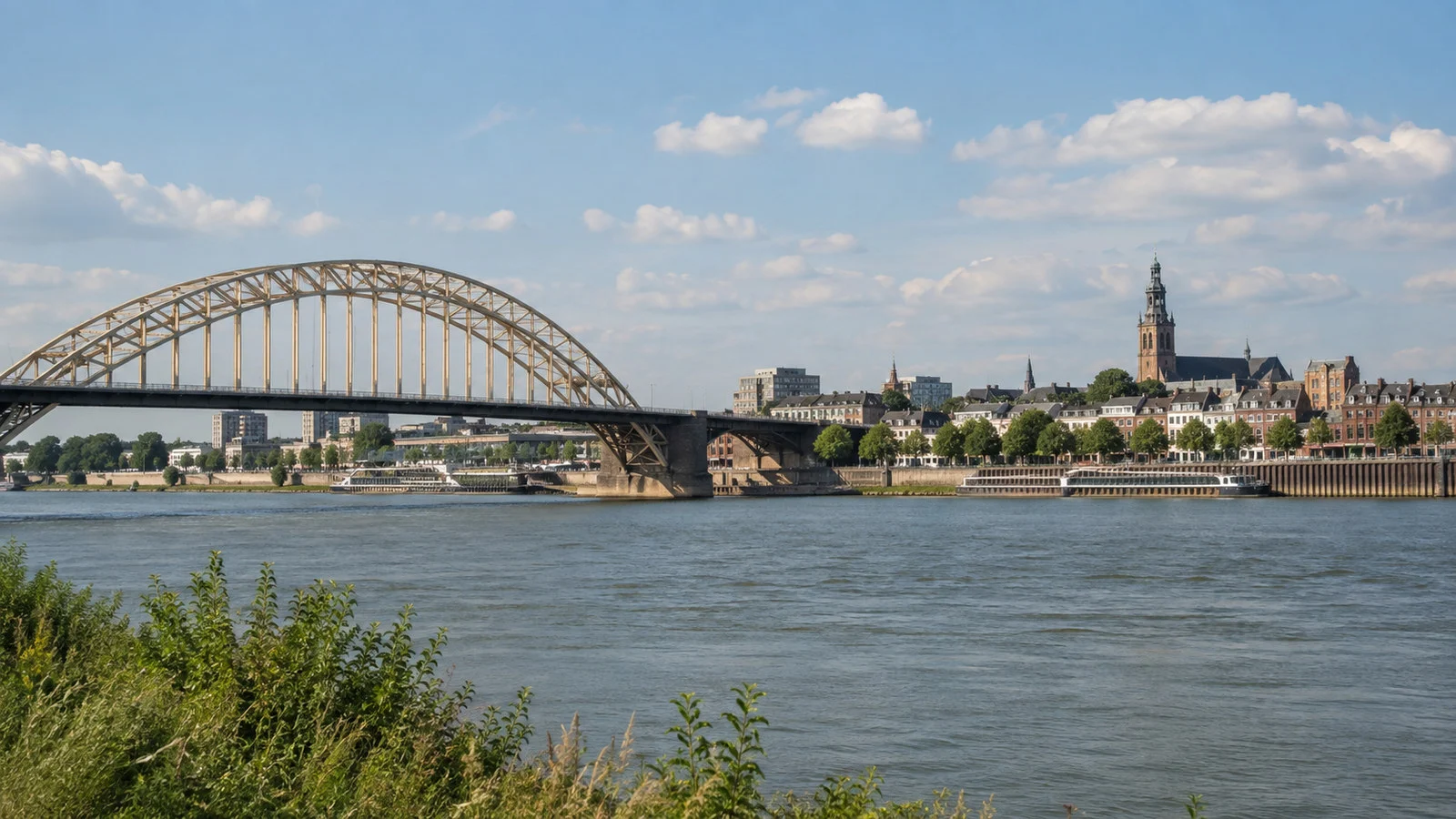 Wide Waal River bridge and Nijmegen waterfront from the opposite bank