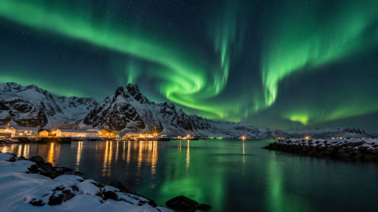 Green northern lights above a snow-covered Norwegian coastal port