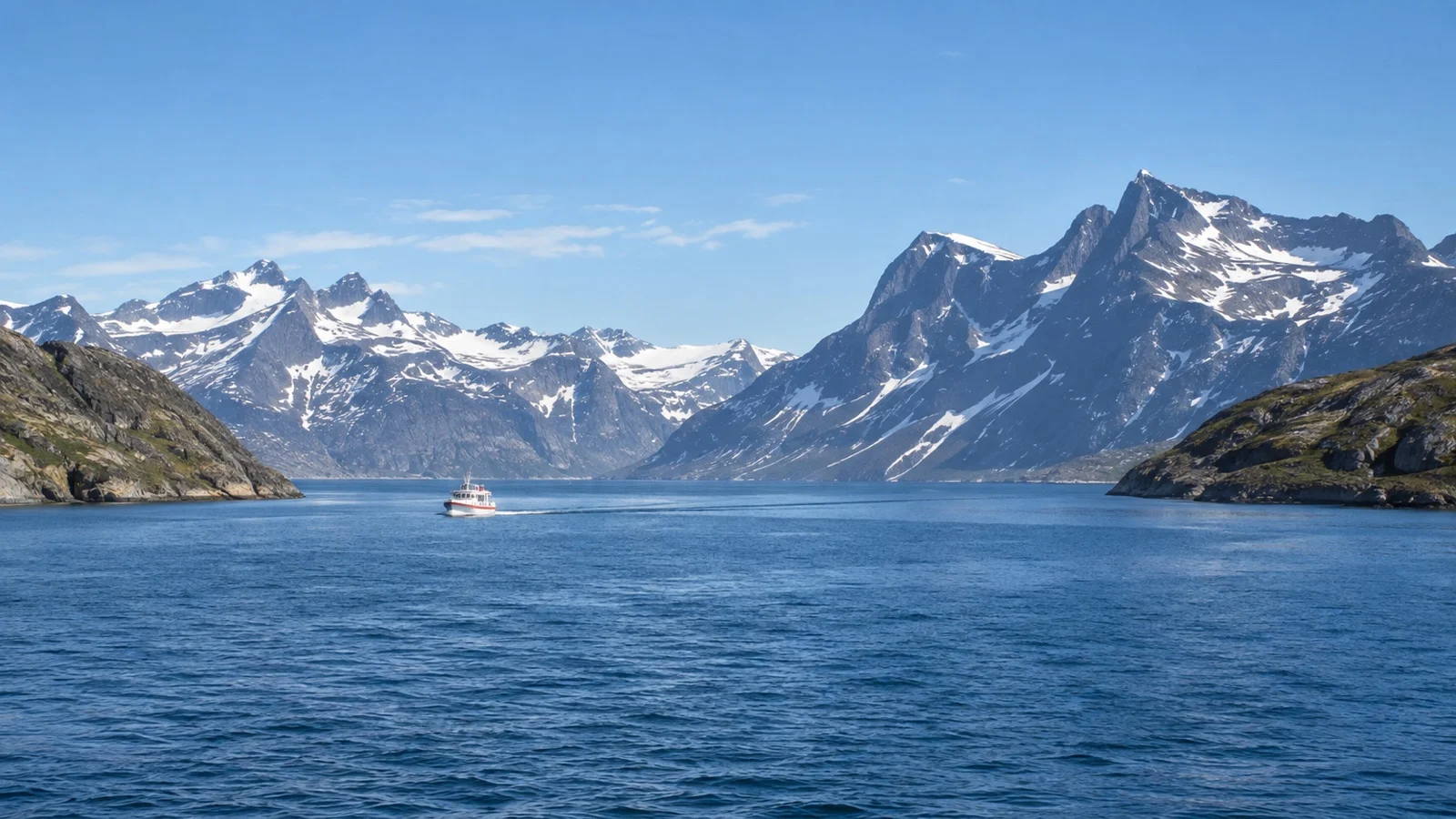 Small sightseeing boat crossing Nuuk Fjord beneath snow-streaked mountains