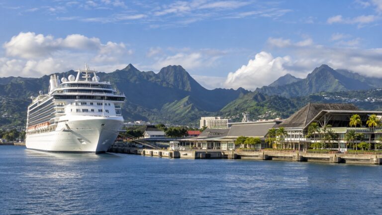 Cruise ship docked at Papeete waterfront on Tahiti with green volcanic mountains