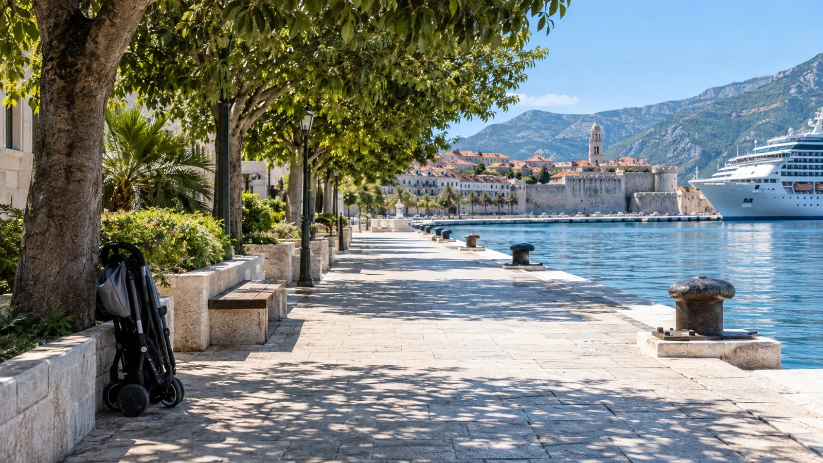 Empty paved port promenade with shade trees and a folded stroller beside the path