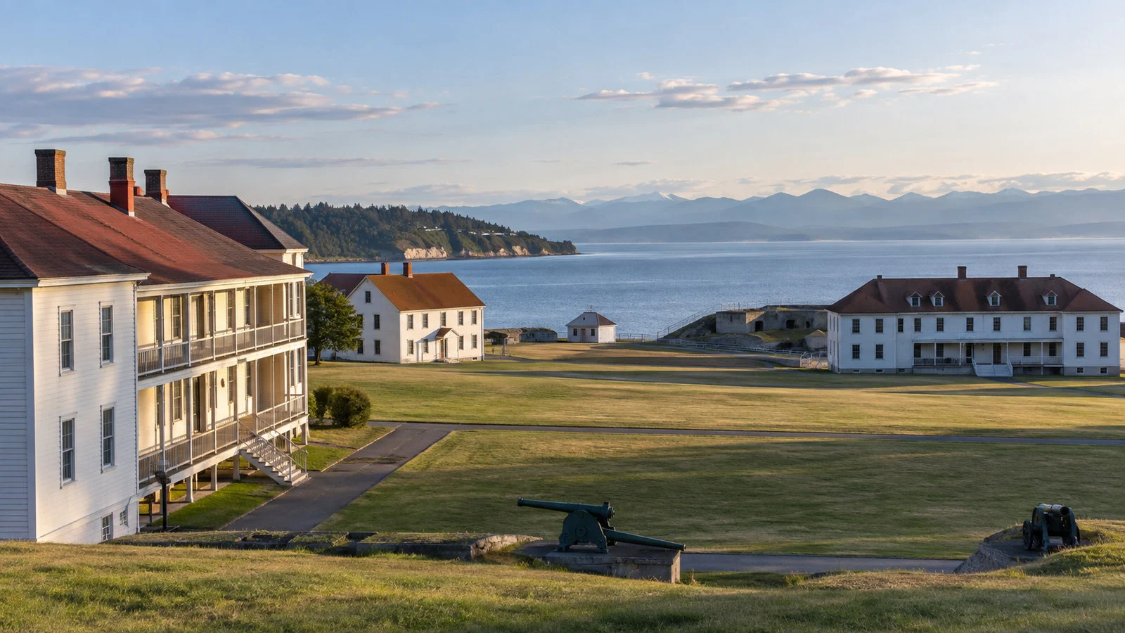 Fort Worden Port Townsend historic military coastal buildings and grassy parade ground with sea behind, no people