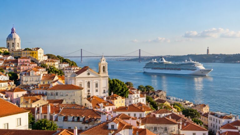 Cruise ship on Lisbon’s Tagus River with Alfama rooftops and the 25 de Abril Bridge