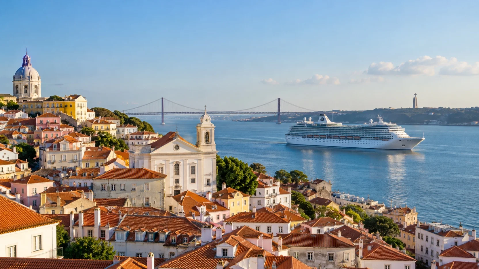 Cruise ship on Lisbon’s Tagus River with Alfama rooftops and the 25 de Abril Bridge