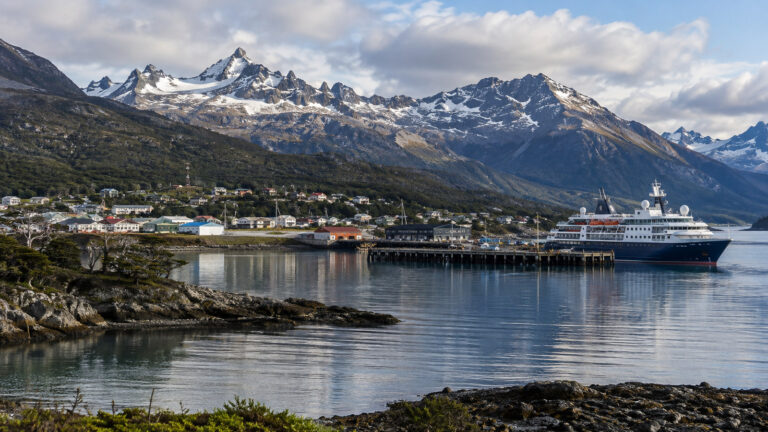 Puerto Williams Chile harbor on Beagle Channel with small expedition cruise ship, Navarino Island mountains and town, no people
