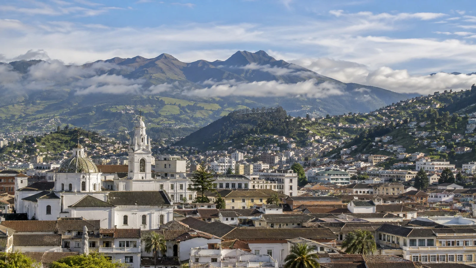 High-altitude Quito cityscape nestled among dramatic green Andean mountains under thin clouds