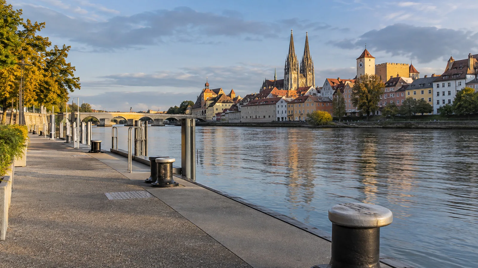 an empty riverside berth with mooring bollards where a river ship has departed, old town in background