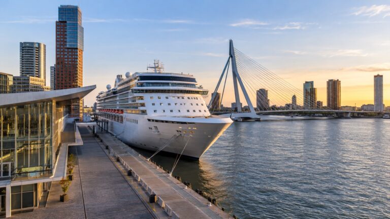 Rotterdam cruise terminal on Wilhelminapier with a large white cruise ship docked beside the Nieuwe Maas river and Erasmus Bridge