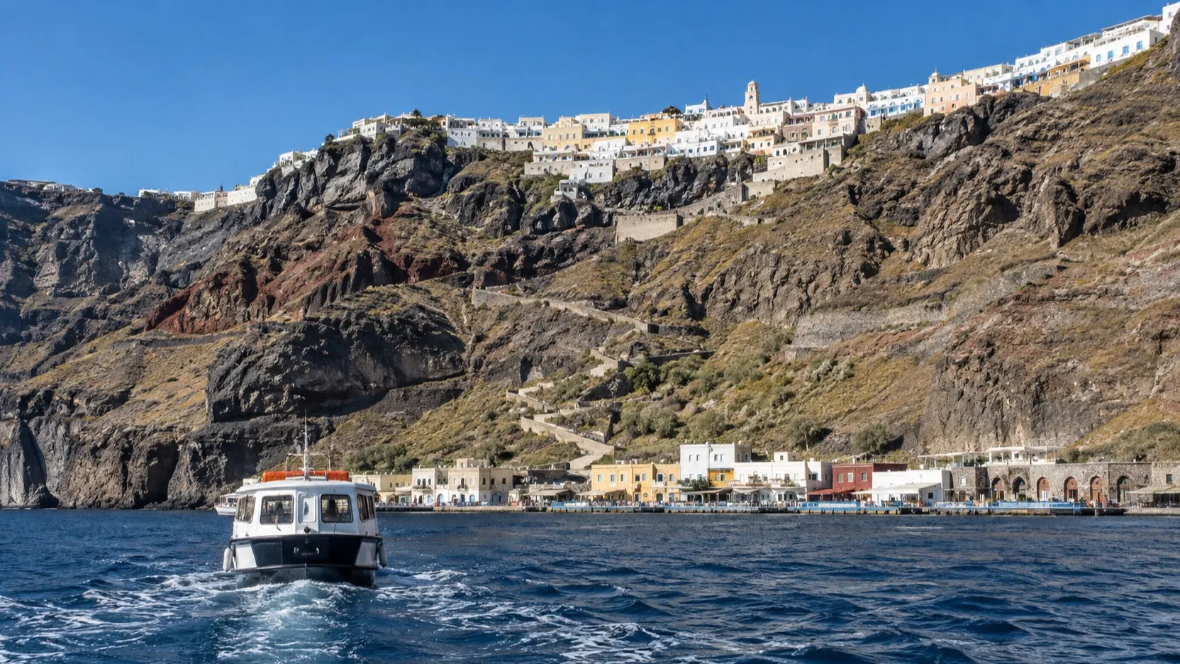 Tender boat arriving at Skala Fira below Santorini’s cliffs