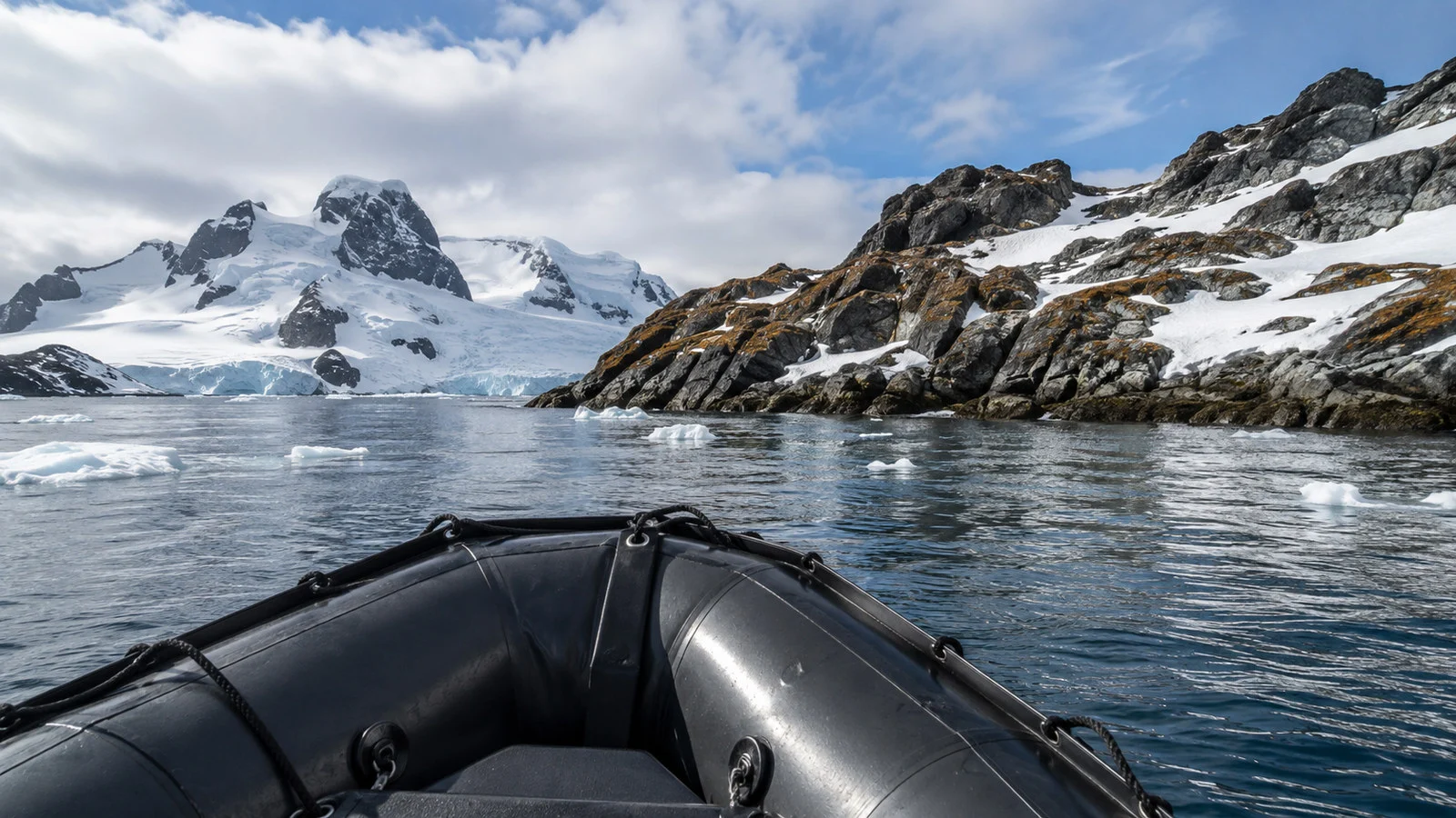 Empty Zodiac inflatable boat approaching South Shetland Islands rocky Antarctic landing with ice and snow, no people