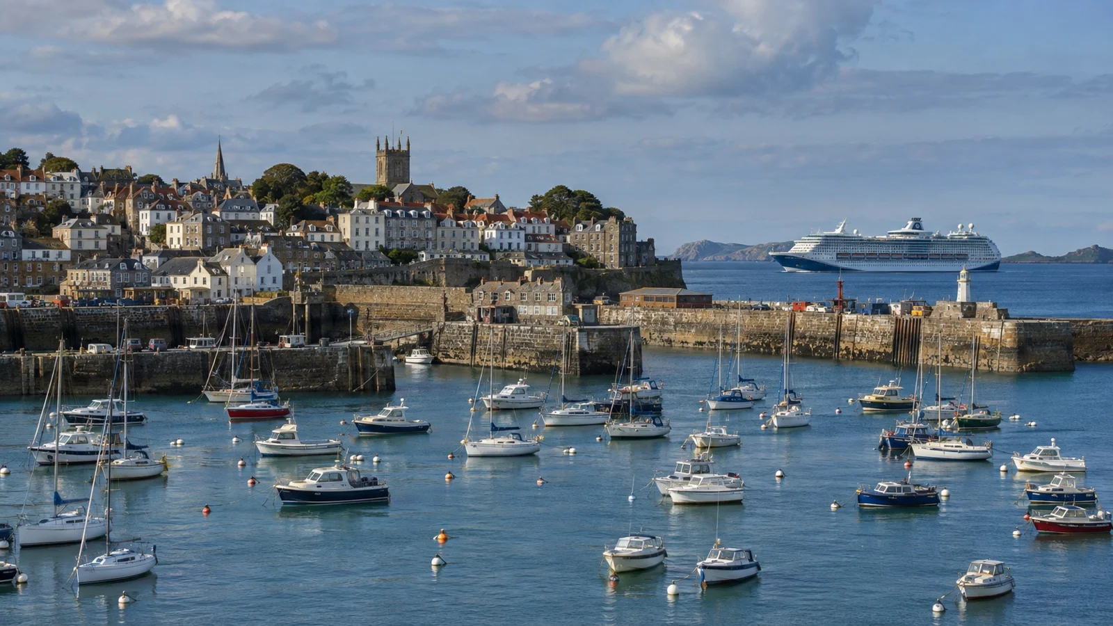 St. Peter Port harbor on Guernsey with cruise ship offshore beyond small boats