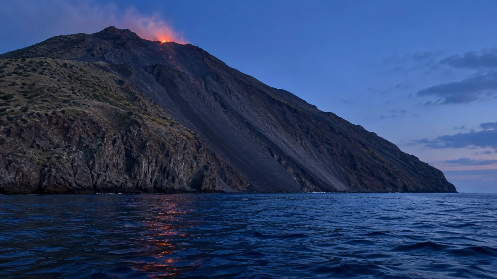 Stromboli’s Sciara del Fuoco volcanic slope descending toward the sea at blue hour.