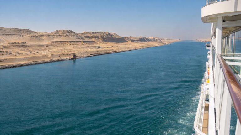 Cruise ship moving through Suez Canal with desert banks on both sides