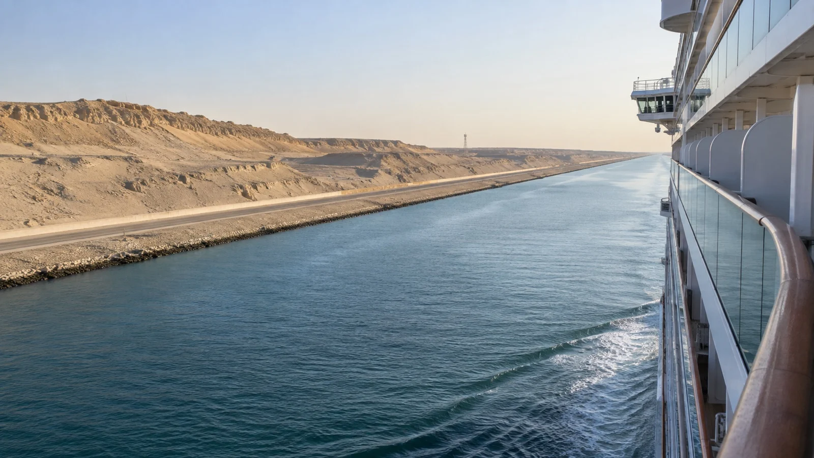 Empty desert canal bank and service road beside passing cruise ship