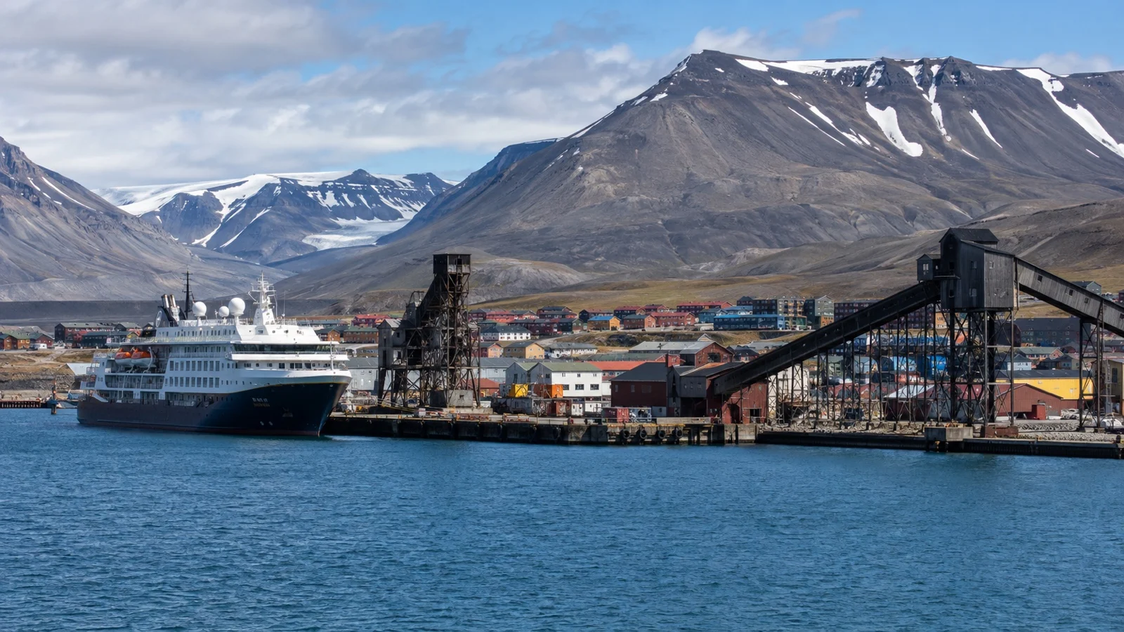 Expedition cruise ship beside Longyearbyen harbor and Arctic mountains