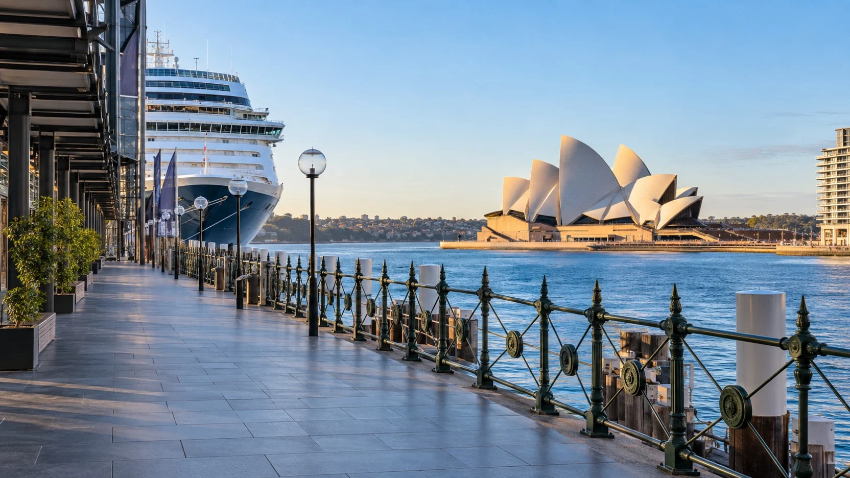 Empty Sydney waterfront walkway beside a cruise ship with the Opera House across the harbor