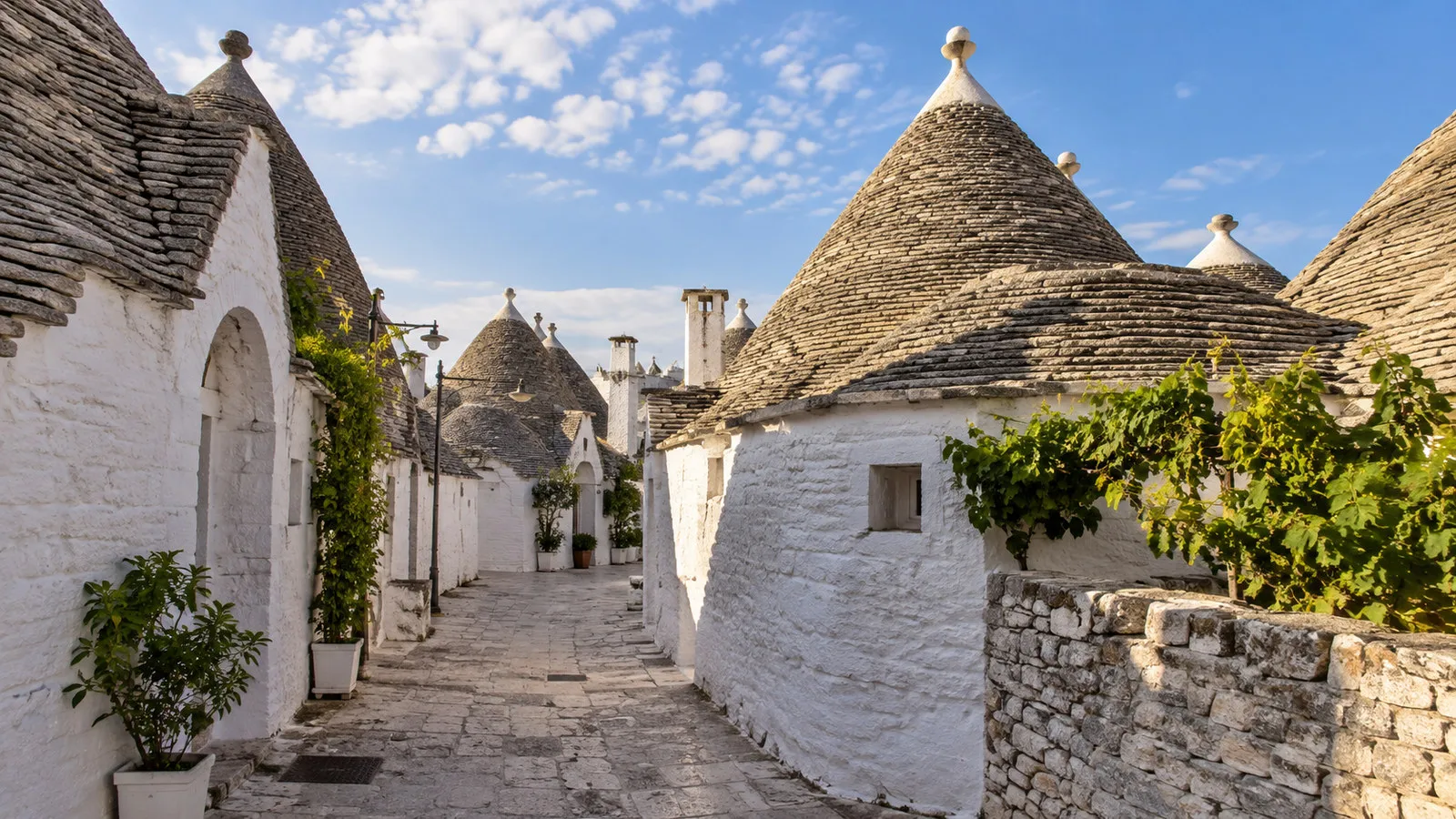 Alberobello Puglia Italy cluster of white trulli houses with conical stone roofs on empty lane, no people