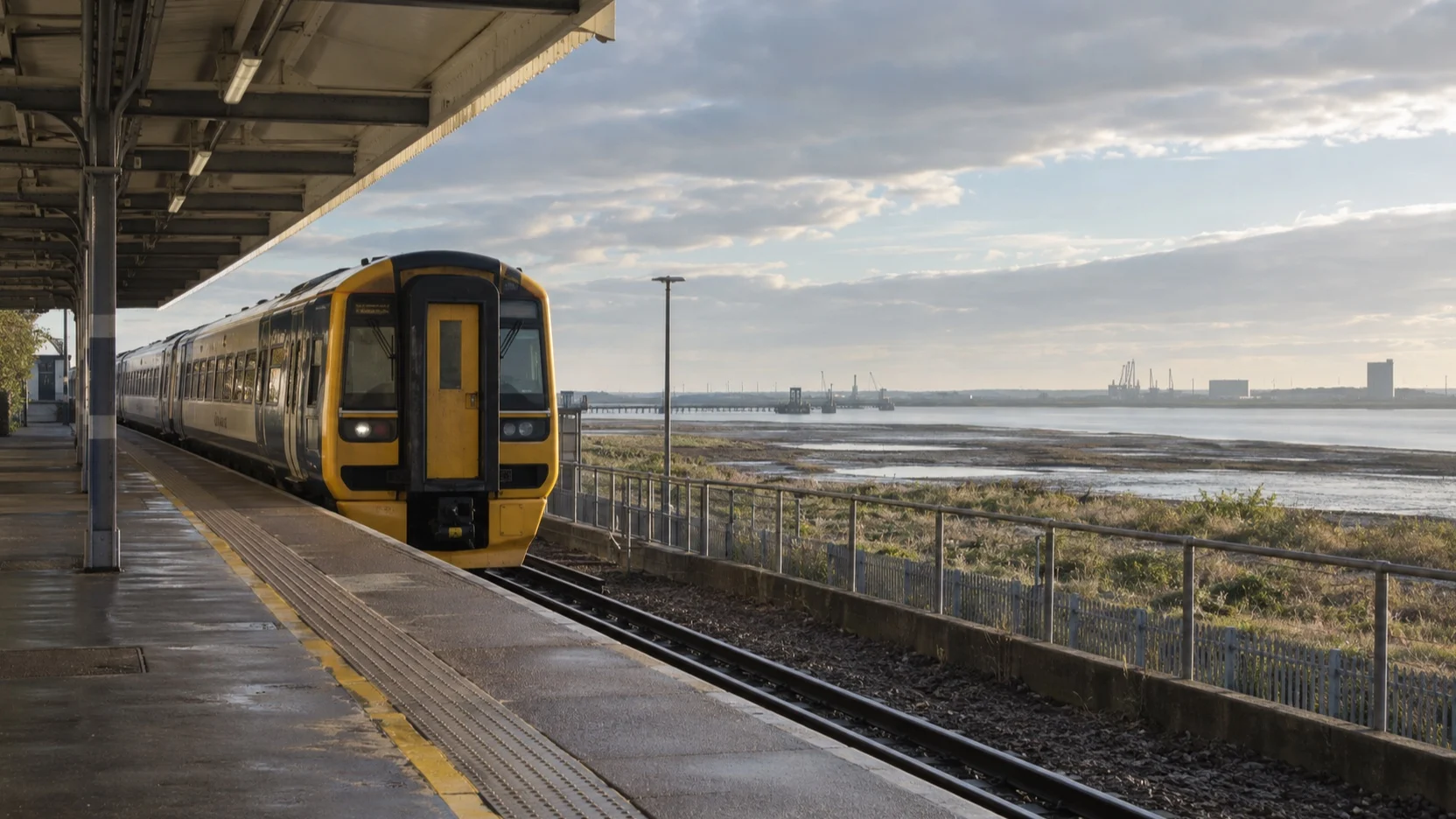 An empty railway platform and commuter train near the Thames estuary at Tilbury