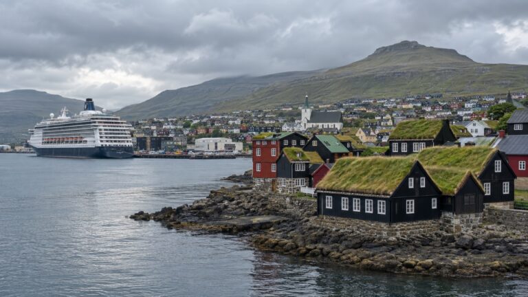 Cruise ship in Tórshavn harbor below turf-roofed buildings