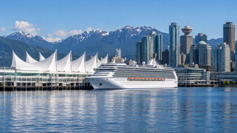 Cruise ship docked beside the white sails of Canada Place with Vancouver’s skyline and mountains beyond
