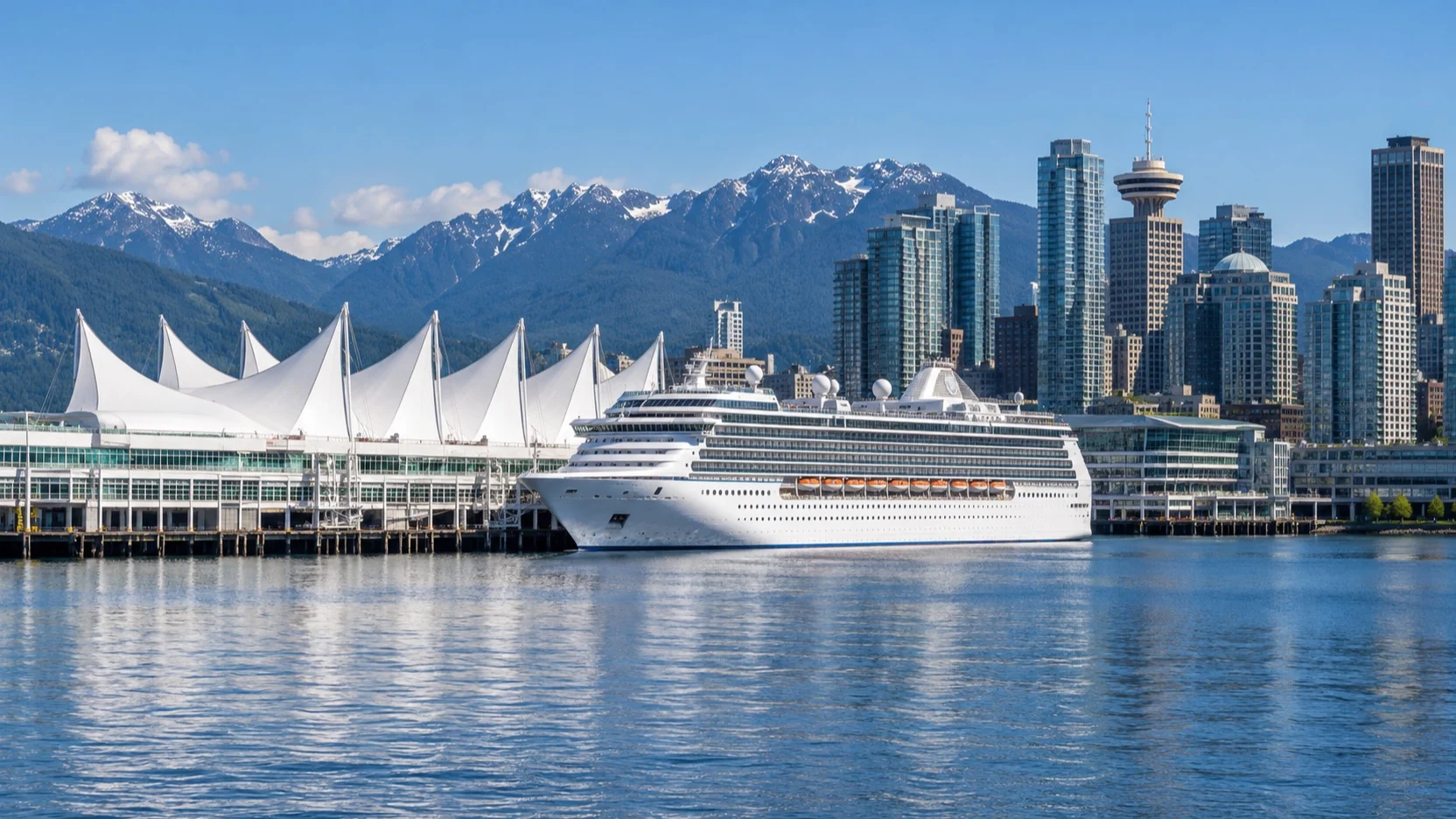 Cruise ship docked beside the white sails of Canada Place with Vancouver’s skyline and mountains beyond