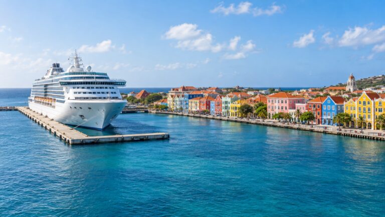 Willemstad Mega Pier with a white cruise ship docked beside the colorful Otrobanda waterfront and Caribbean water