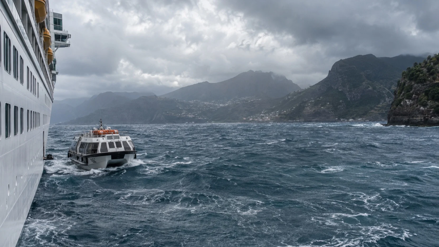Tender boat beside a cruise ship in choppy weather